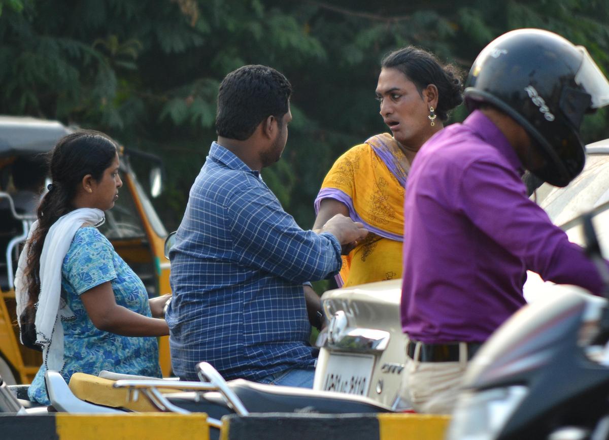 Una persona transgénero mendigando en un cruce de tráfico. 