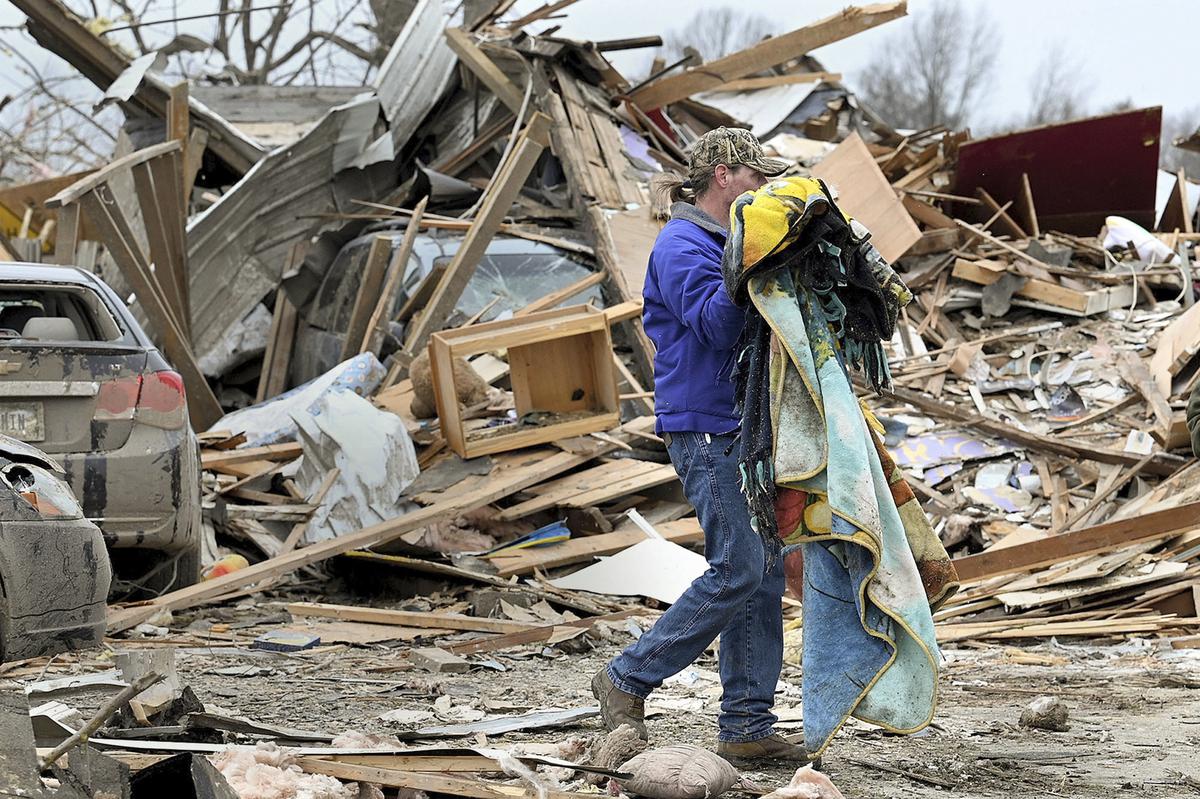 Sullivan resident Joe Reed carries blankets to a car as he and his family salvage what they can, Saturday, April 1, 2023, in Sullivan, Indiana, after a tornado moved through the area late the night before.
