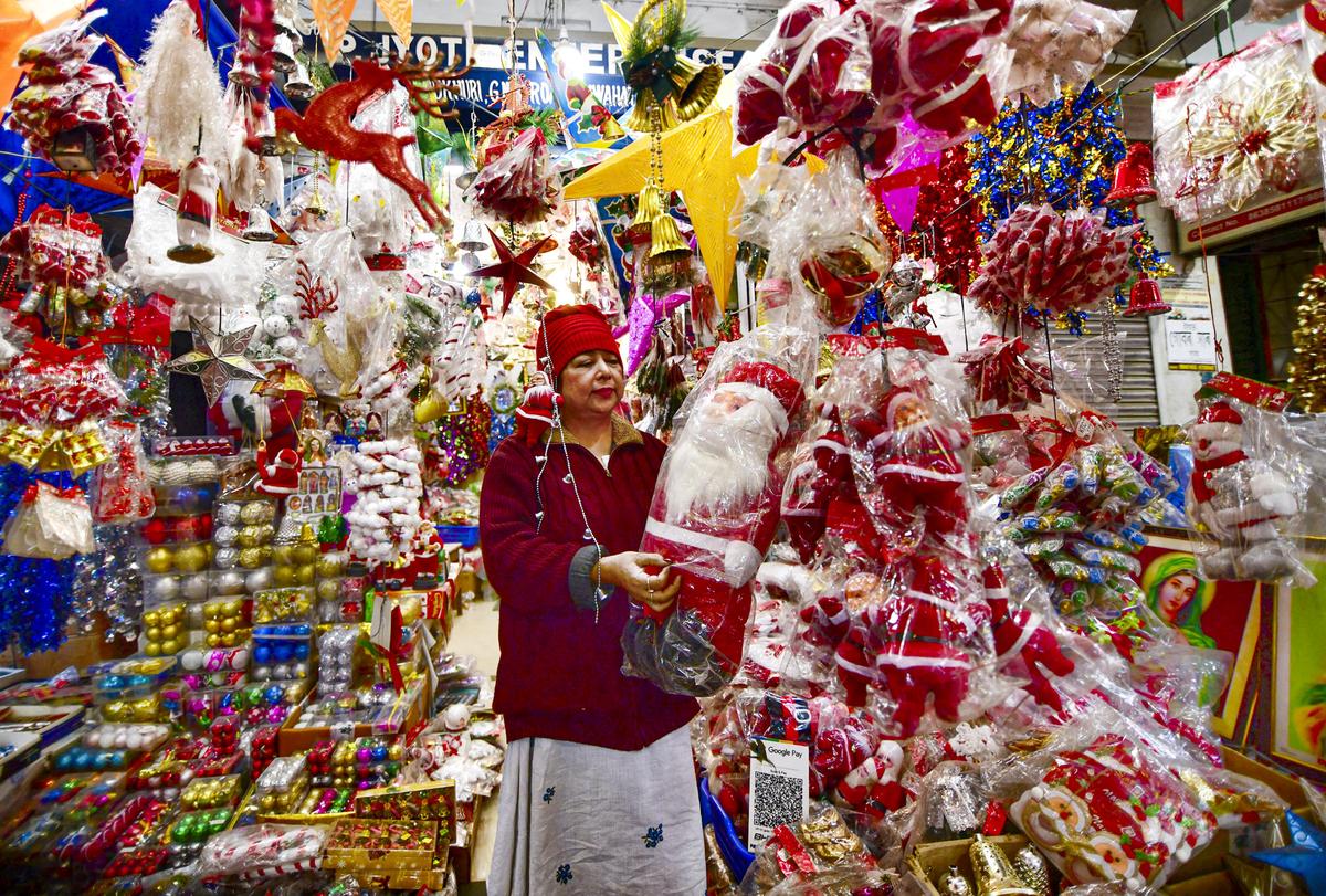 A vendor arranges Santa Claus dolls and other Christmas decorations at her stall in a market ahead of Christmas