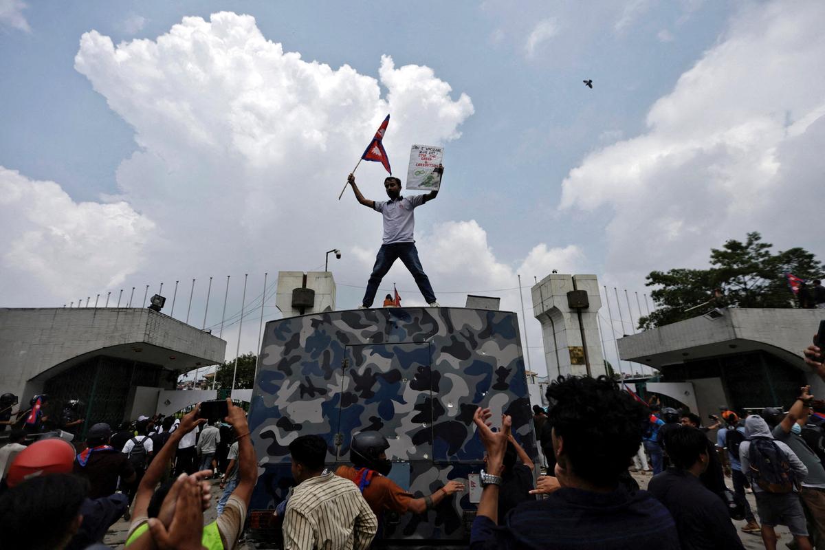 A demonstrator waves a flag as he stands atop a vehicle near the entrance of the Parliament during a protest against corruption and government’s decision to block several social media platforms, in Kathmandu. 