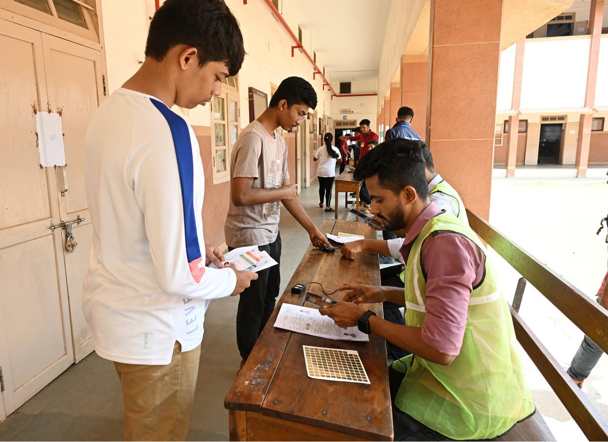 Officials conducting checks before allowing students to enter the exam centre at Canara College.