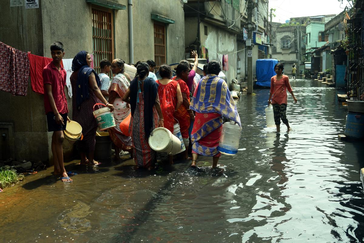 Residents wade through sludge-filled, water-logged alleys to get to the water tankers which supply them their daily share of water. 