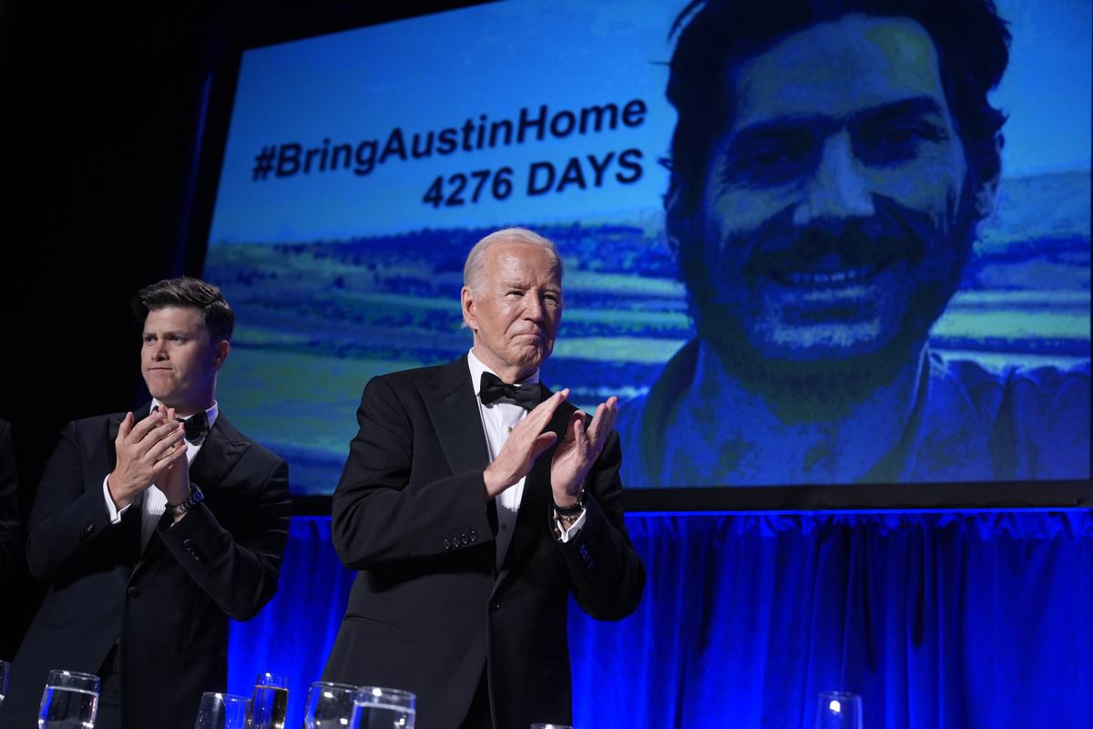 Host Colin Jost, left, and President Joe Biden applaud as an image of Austin Tise, an American journalist detained in Syria, appears on screen at the White House Correspondents’ Association Dinner.