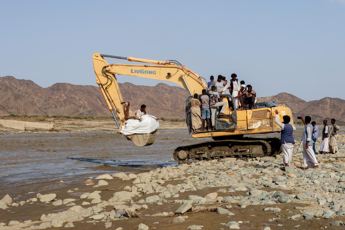 Aid and people are transported on an excavator following devastating floods, in Port Sudan, on August 26, 2024