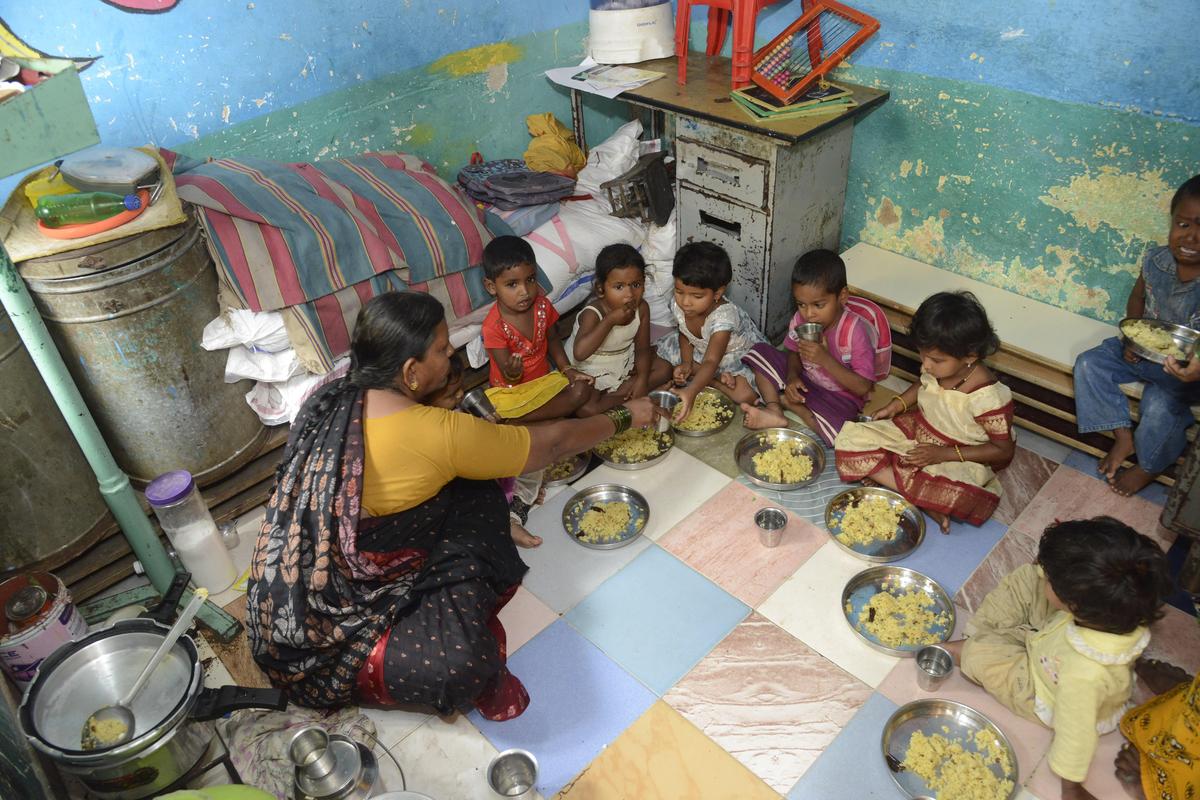 Staff serving food to children at an anganwadi.