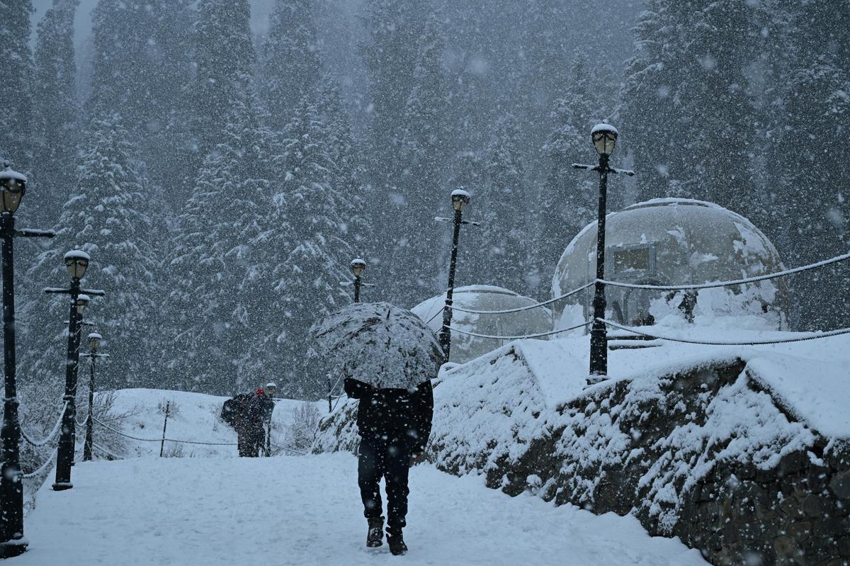 Un hombre camina bajo un paraguas en Gulmarg durante una nevada fresca en la famosa estación de esquí de Gulmarg, a 55 kilómetros de Srinagar, el 21 de diciembre de 2025. 