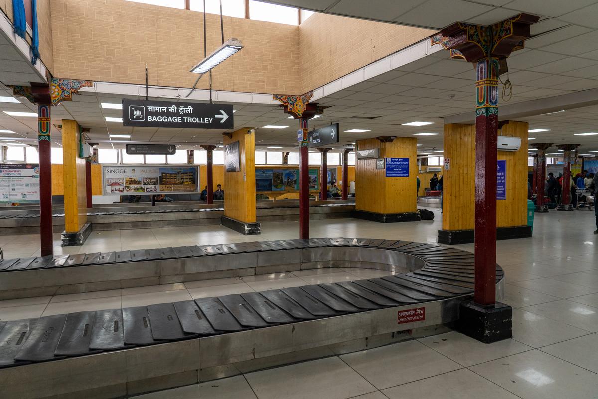 People waiting at baggage claim conveyor belts in the arrival area of Kushok Bakula Rimpochee Airport lead People waiting at baggage claim conveyor belts in the arrival area of Kushok Bakula Rimpochee Airport lead