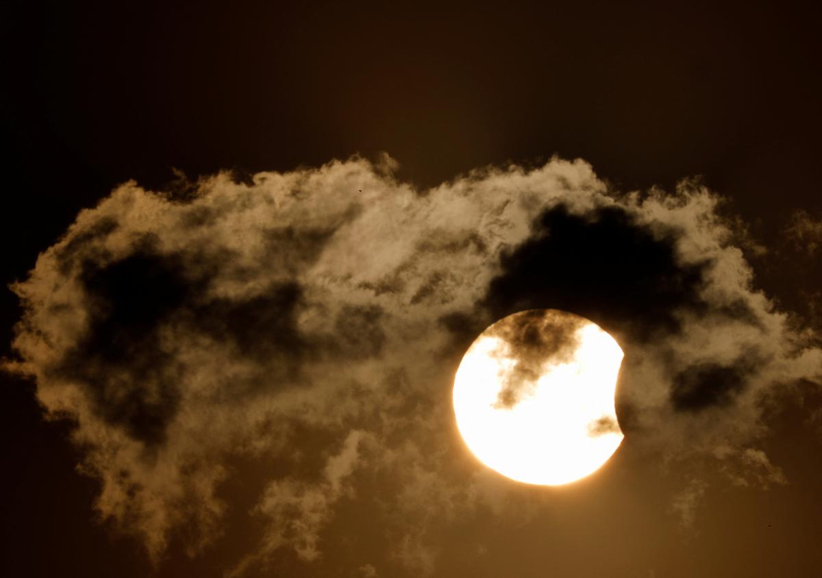 A partial solar eclipse is pictured behind the cloud during the sunset in Kathmandu, Nepal October 25, 2022. 