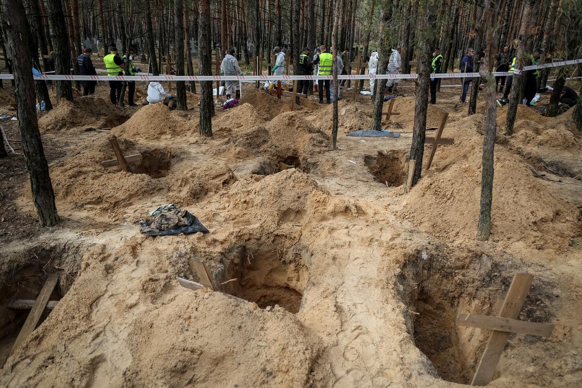 Police and experts work at a place of mass burial during an exhumation in the town of Izium, recently liberated by Ukrainian Armed Forces, in Kharkiv region on September 17.