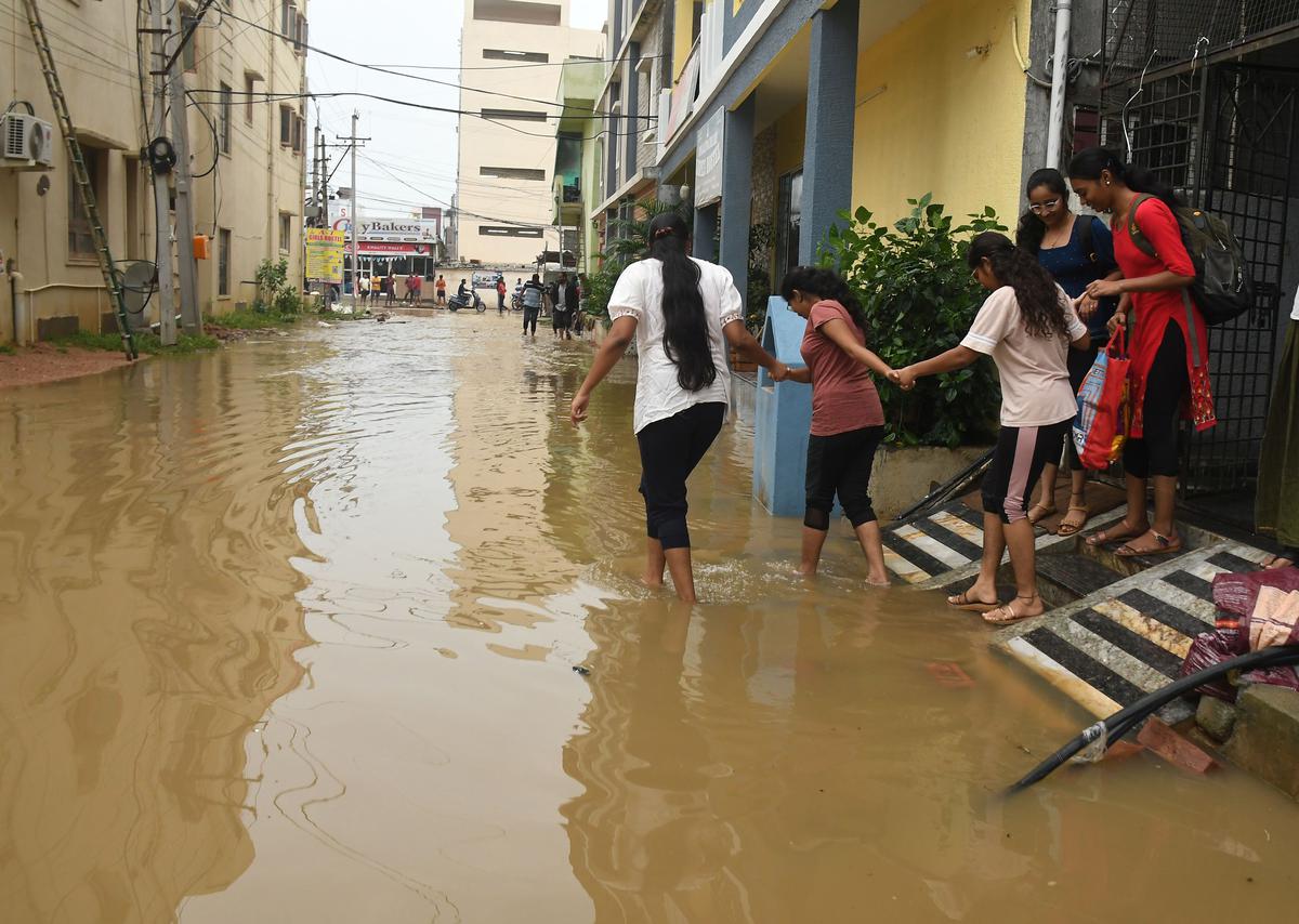 Students of a girls’ hostel tread carefully in the flood water that inundated roads of Maisammaguda area on the outskirts of Hyderabad on Tuesday.