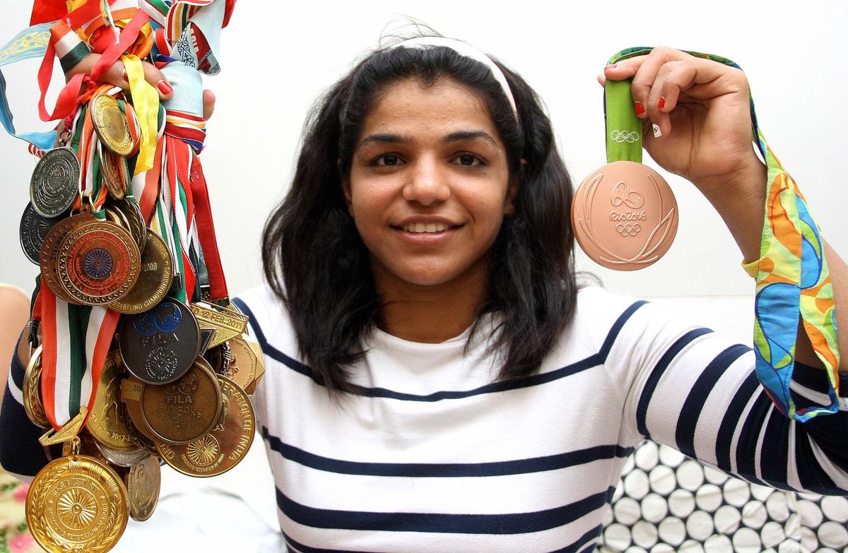 Sakshi Malik holding all her previous medals in one hand and the Olympic bronze in the other, at her home, in Rohtak.