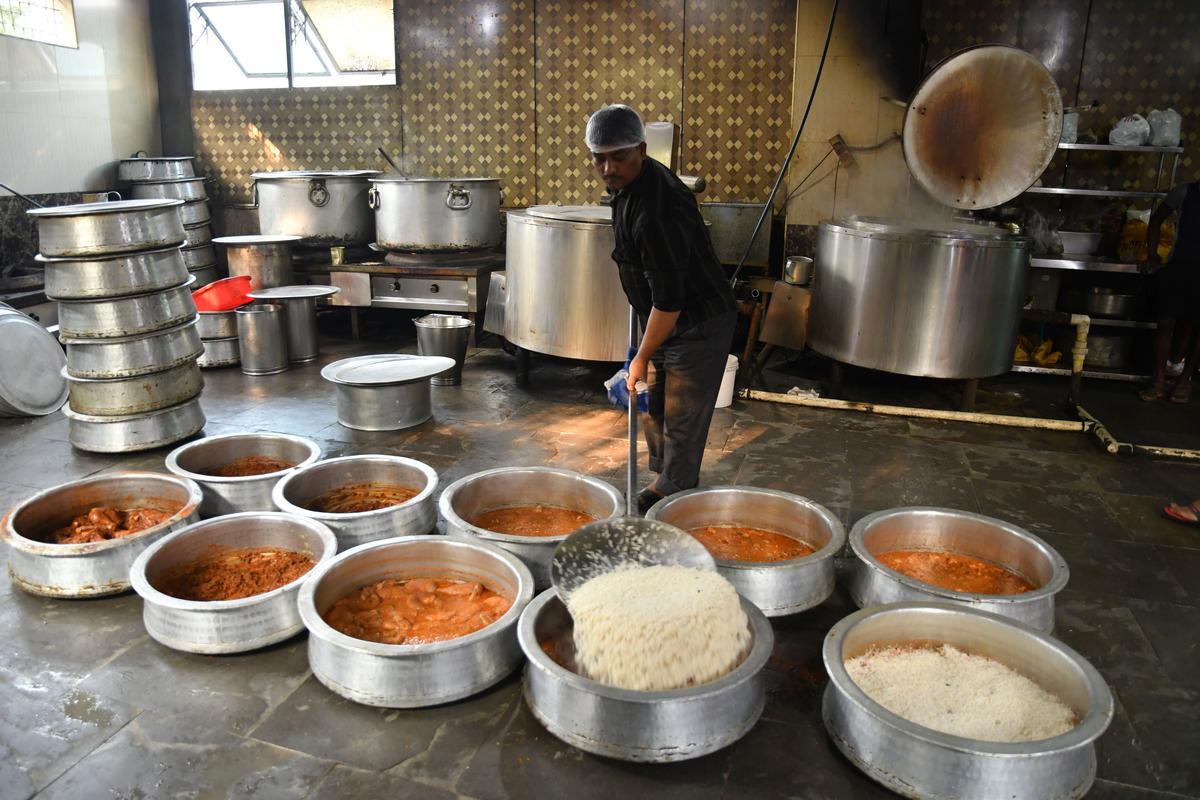 A chef deftly spreads a layer of partly cooked rice on the marinated meat in the biryani vessel where it will get cooked for 45 minutes.