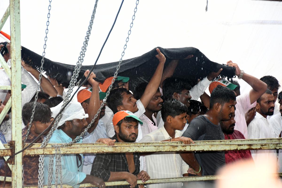 People using a woollen blanket to protect themselves from the rain at Congress MP Rahul Gandhi’s public meeting in Jewargi, Kalaburagi district, on April 28, 2023. 