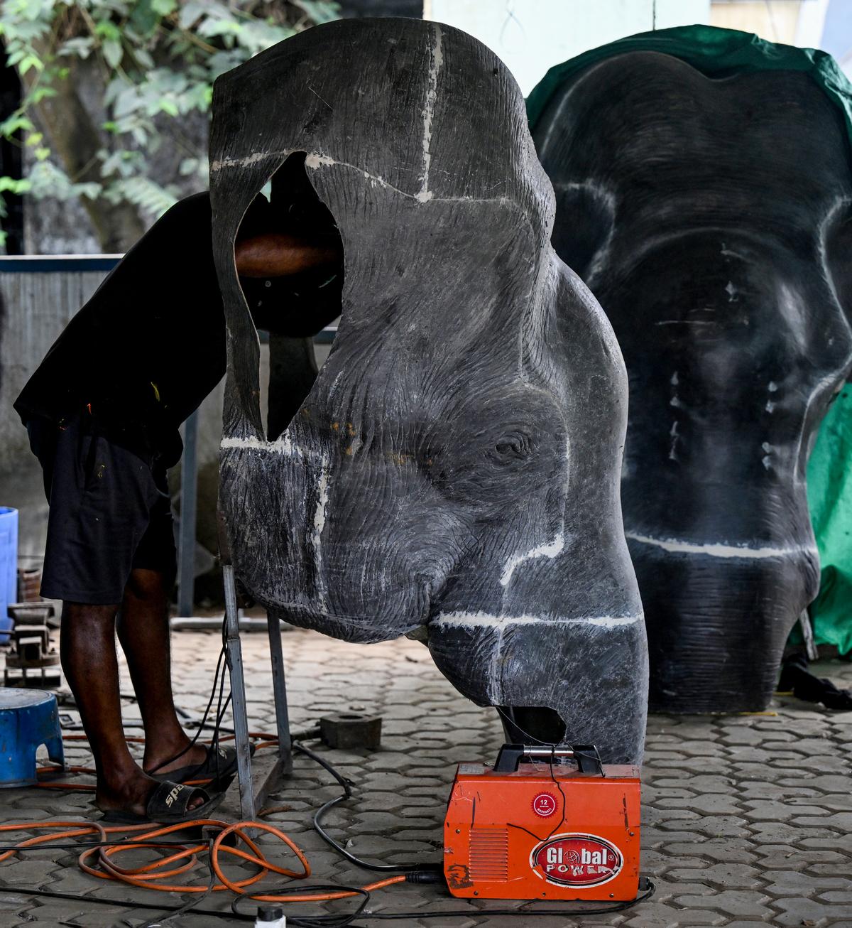 A worker puts together material that will go on to become a section of the head of a mechanical elephant 