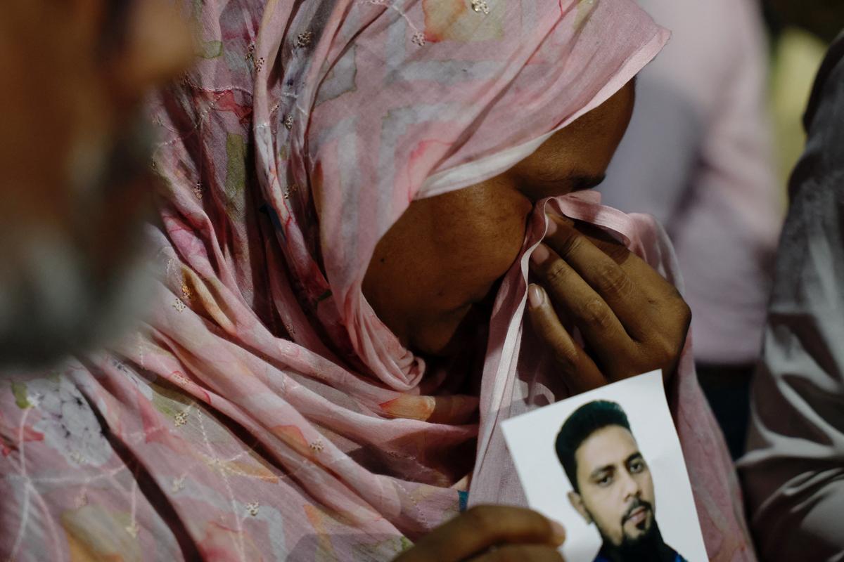 A relative mourns while holding a picture of a missing person following a fire that broke out at a garment factory and a chemical warehouse in Dhaka