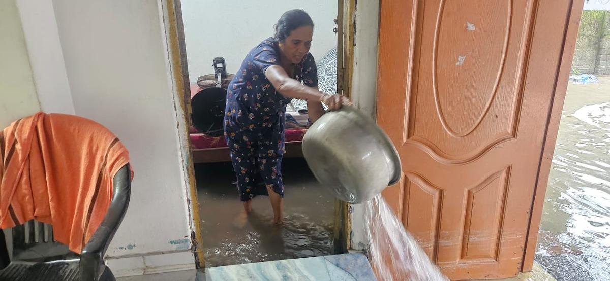 A woman in Chellanam tries to clear floodwater from her house amid sea incursion on June 15.