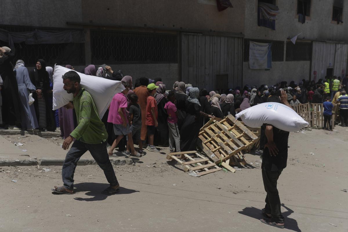 Palestinians carry bags of flour distributed by the World Food Programme (WFP) in Gaza City. Palestinians carry bags of flour distributed by the World Food Programme (WFP) in Gaza City.