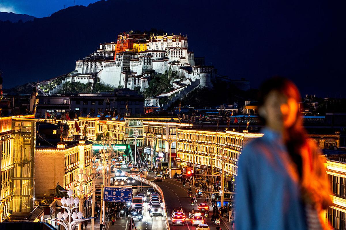 A view of the illuminated city streets of Lhasa, with Potala Palace in the distance.