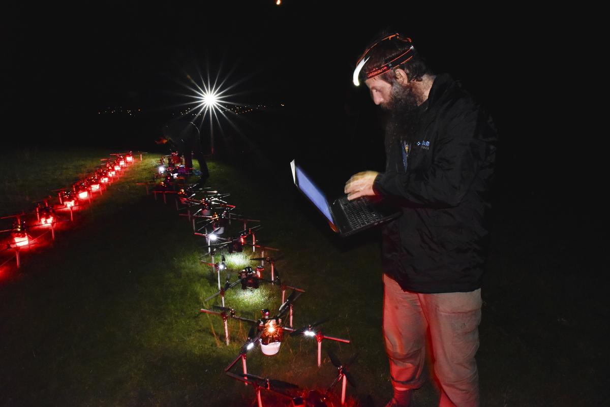 In this handout photo Gabor Vasarhelyi, physicist and researcher of the Department of Biological Physics at Eötvös Loránd University, is using his computer to set a swarm of 100 quadcopters to fly autonomously during an experiment near Budapest, Hungary, Thursday, Oct. 21, 2021. 