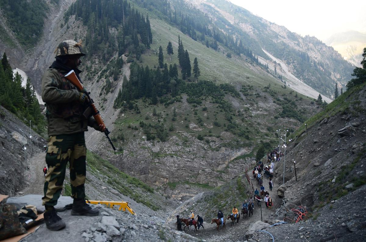 An Army officer stands guard as pilgrims cross the mountain trail to the Amarnath cave on the Baltal route.