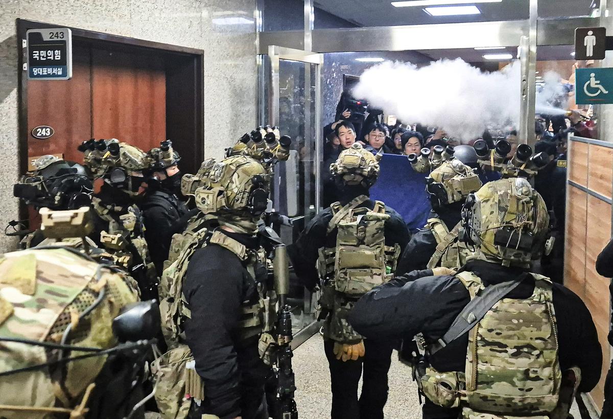 A National Assembly staff sprays fire extinguishers to block soldiers entering the main hall of the National Assembly in Seoul, South Korea, Wednesday, Dec. 4, 2024. 