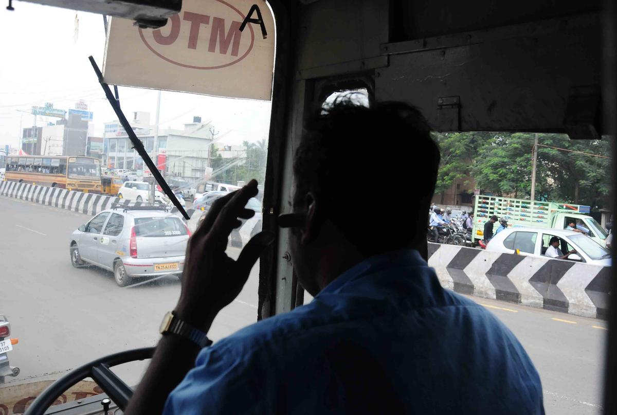 ব্যস্ত রাস্তায় গাড়ি চালানোর সময় ব্লুটুথের সাথে সেল ফোন ব্যবহার করে একটি বাস ড্রাইভার।