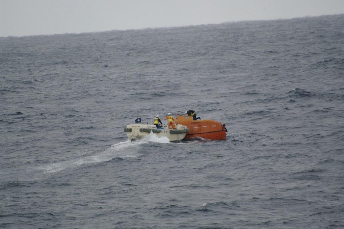Japan Coast Guard crews check a life boat drifting at sea near the site of a cargo ship that sank 