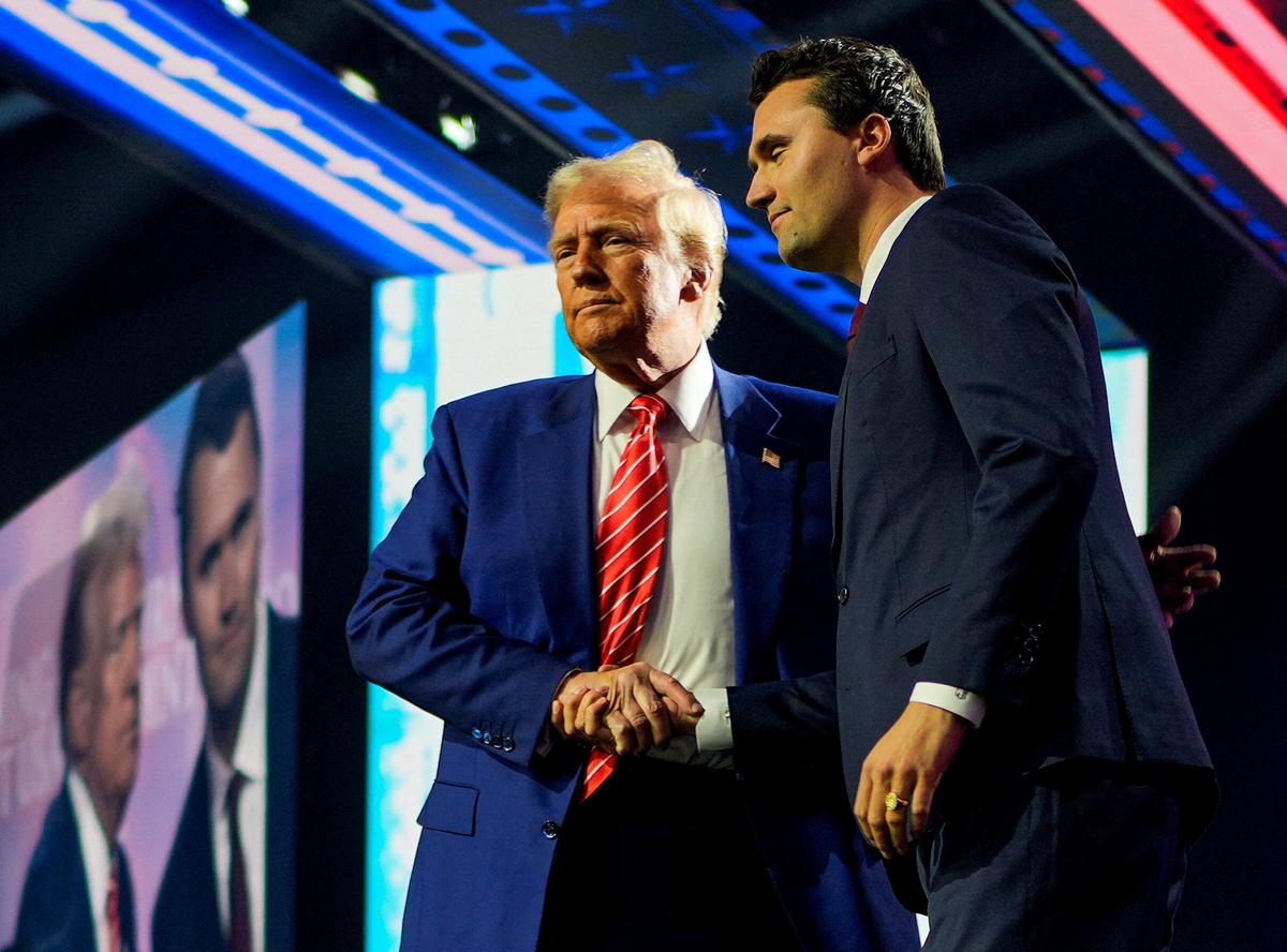 U.S. President Donald Trump shakes hands with Turning Point USA founder Charlie Kirk in Arizona. File