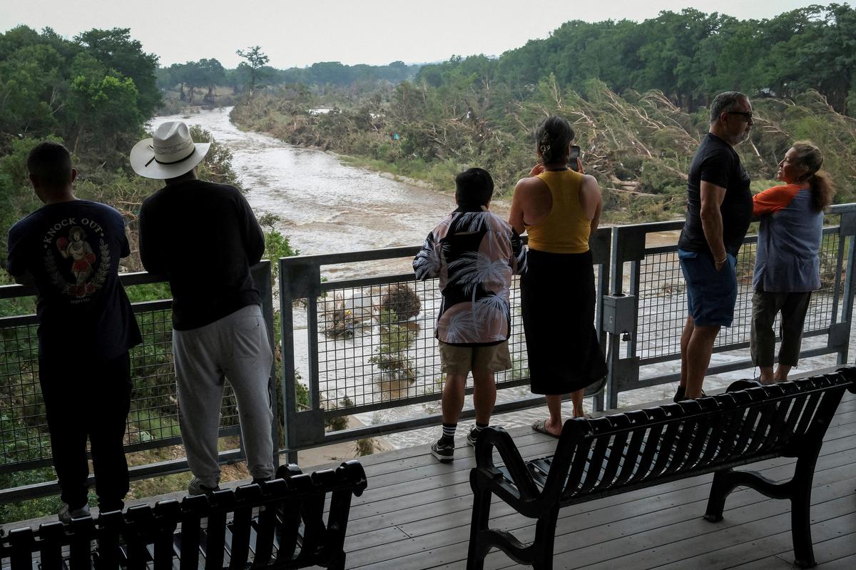People look at the Guadalupe river, following flash flooding, as they gather after receiving a SMS alerting on potential floods in the area, in Kerrville, Texas, U.S. July 6, 2025.     