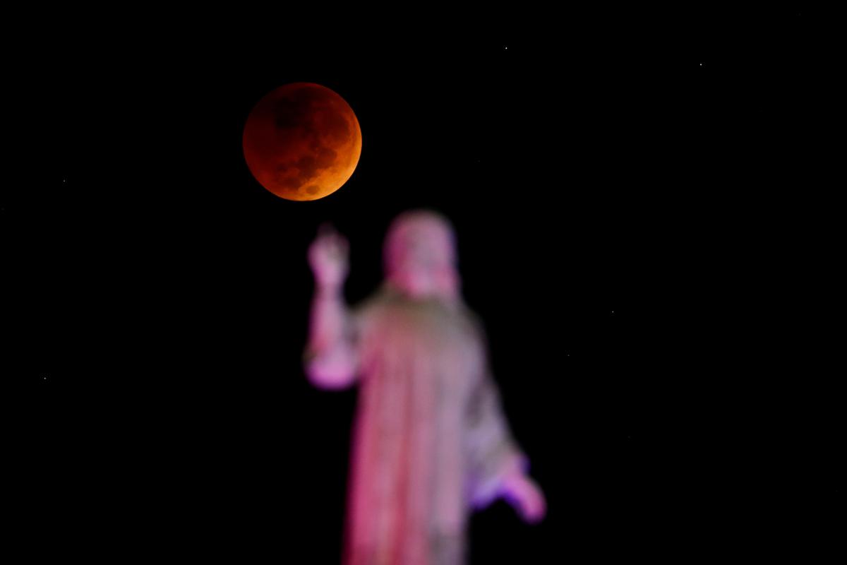 The moon and a statue are seen during a lunar eclipse in San Salvador, El Salvador, November 8, 2022. 