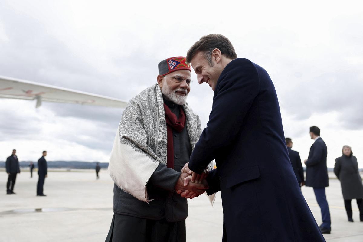 French President Emmanuel Macron, right, shakes hands with Indian Prime Minister Narendra Modi as the latter emplanes for Washington