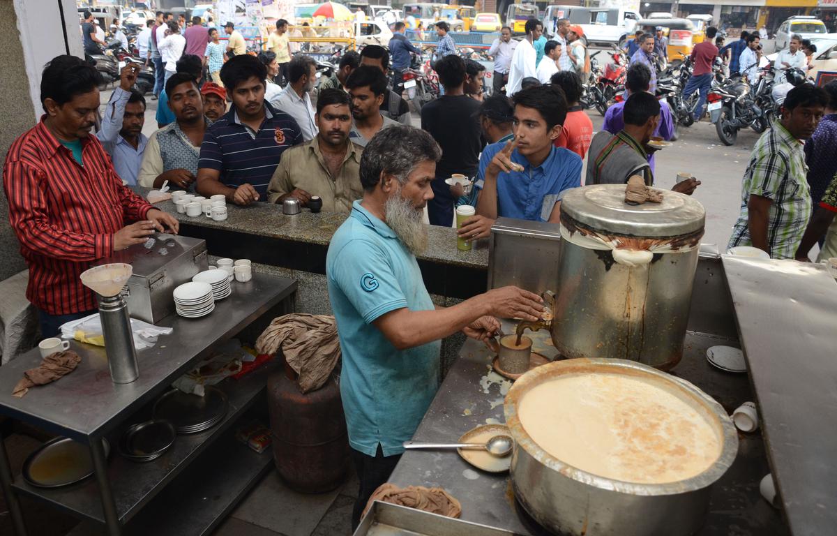 Customers queue up outside a tea shop at Toli Chowki Cross Road in Hyderabad. 