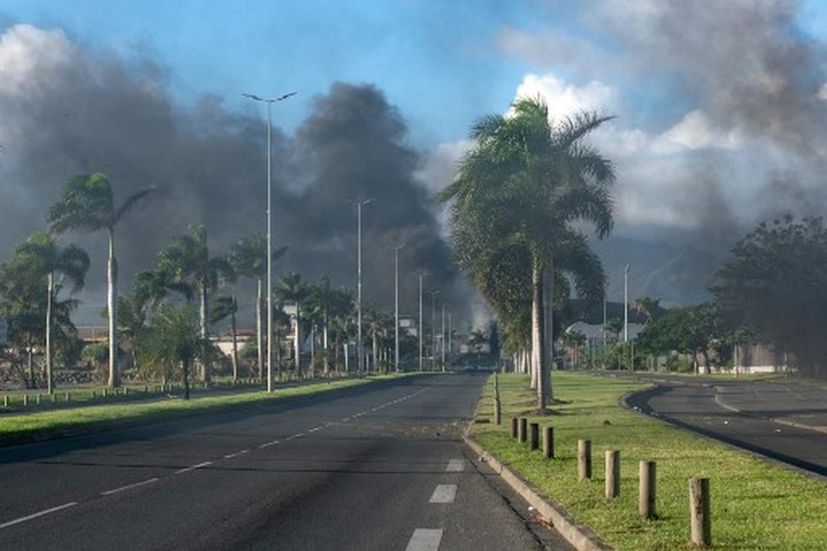 Smoke from fires set by rioters rises on the outskirts of Noumea on May 16, 2024, amid protests linked to a debate on a constitutional bill aimed at enlarging the electorate for upcoming elections of the overseas French territory of New Caledonia. France deployed troops to New Caledonia’s ports and international airport, banned TikTok and imposed a state of emergency on May 16 after three nights of clashes that have left four dead and hundreds wounded. Pro-independence, largely indigenous protests against a French plan to impose new voting rules on its Pacific archipelago have spiralled into the deadliest violence since the 1980s, with a police officer among several killed by gunfire. 