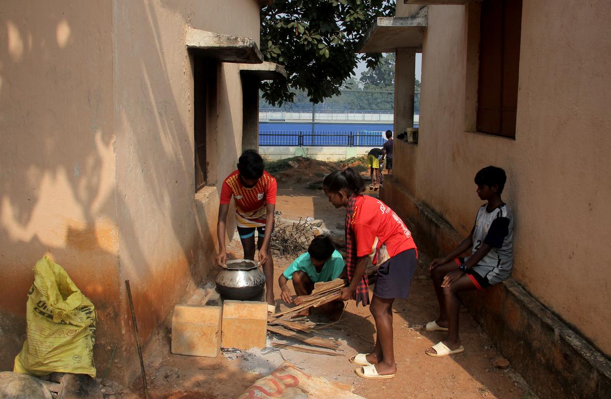 Trainees at the Gurundia hockey stadium prepare firewood to make their lunch after their morning training session. 