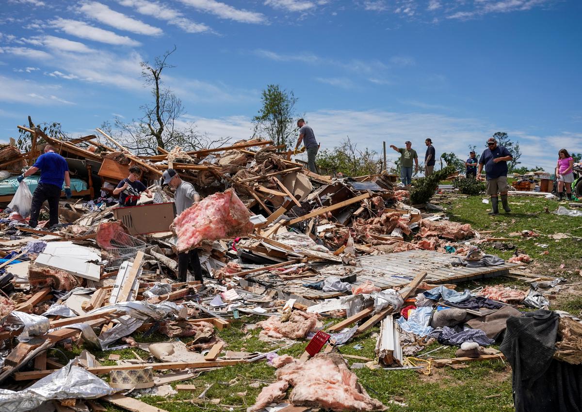 People clean up the debris from a destroyed home in the neighborhood after a series of tornadoes hit Laurel County, in London, Kentucky, U.S. on May 18, 2025.  