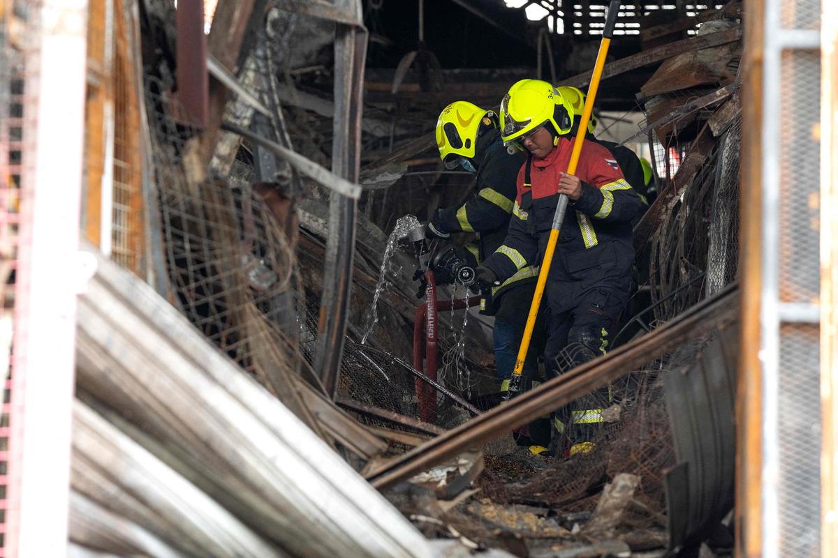 Firefighters walk through the wreckage and debris after a fire at a pet market next to Chatuchak market in Bangkok on June 11, 2024. Firefighters walk through the wreckage and debris after a fire at a pet market next to Chatuchak market in Bangkok on June 11, 2024.