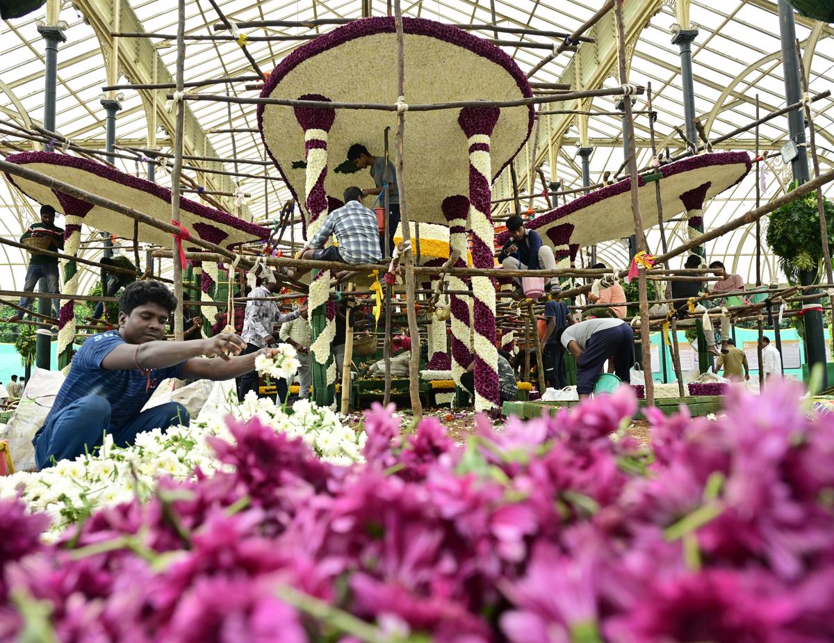 The workers create models using various flowers in front of the 218th Flower Show at Lalbagh Glass House in Bengaluru on August 5, 2025.  