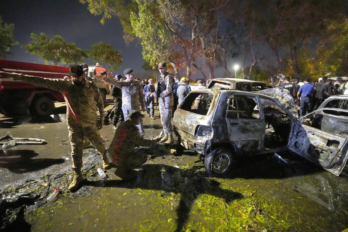 Security officials examine damage cars at the site of an explosion that caused injures and destroyed vehicles at outside the Karachi airport, Pakistan, Monday, Oct. 7, 2024. 