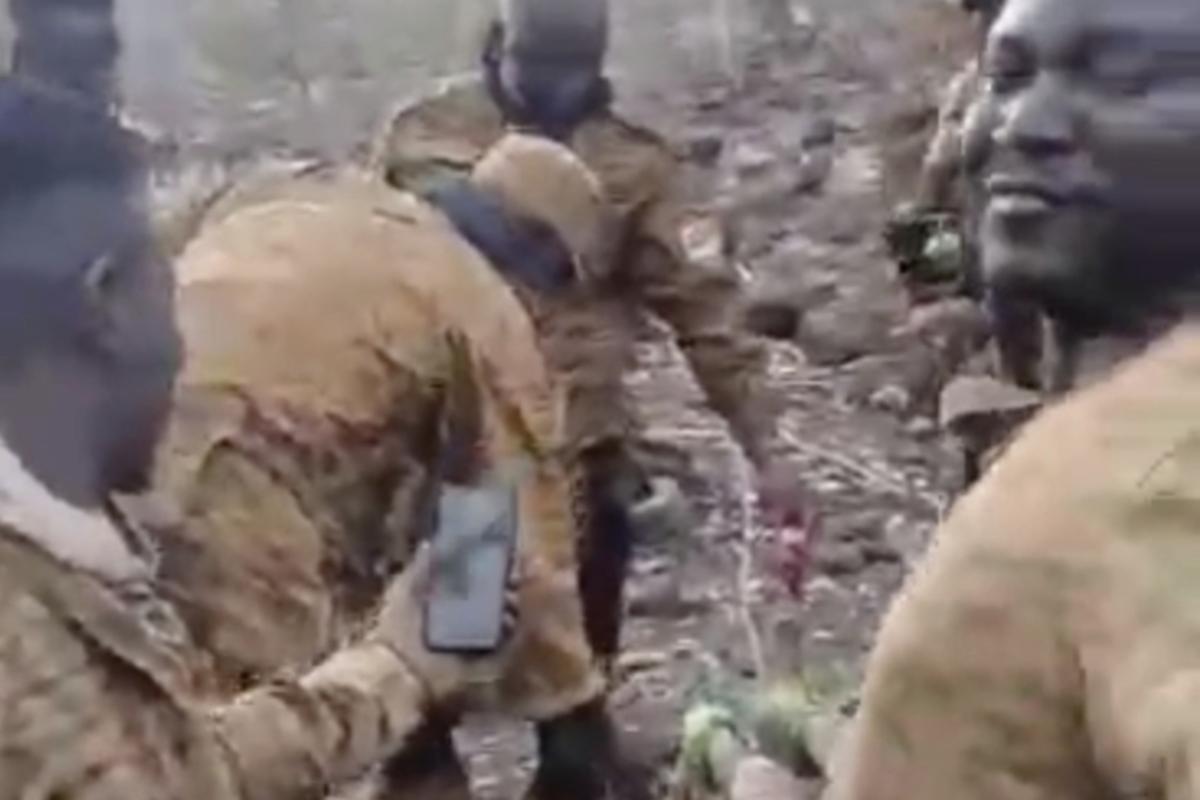 In this image from video posted on a Wagner Group-affiliated Telegram channel in July 2024, men in Burkina Faso military uniforms stand around a dead body lying on the ground as it was cut into pieces. In this image from video posted on a Wagner Group-affiliated Telegram channel in July 2024, men in Burkina Faso military uniforms stand around a dead body lying on the ground as it was cut into pieces.