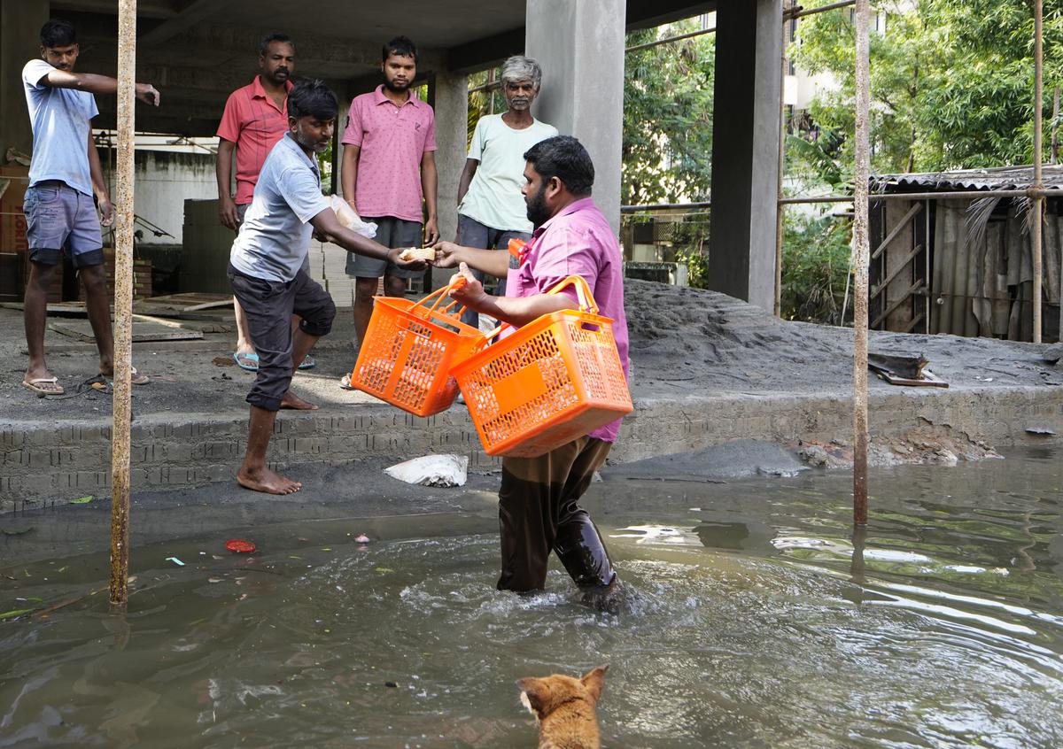 A volunteer distributes food in a waterlogged area