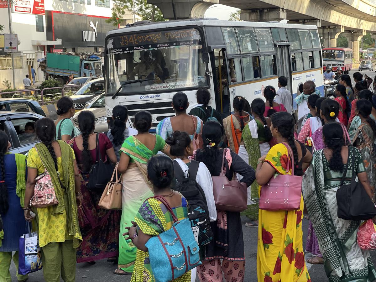 A large number of women who work in the garment industry wait to board buses at the Muthurayanagar bus stop in Bengaluru.