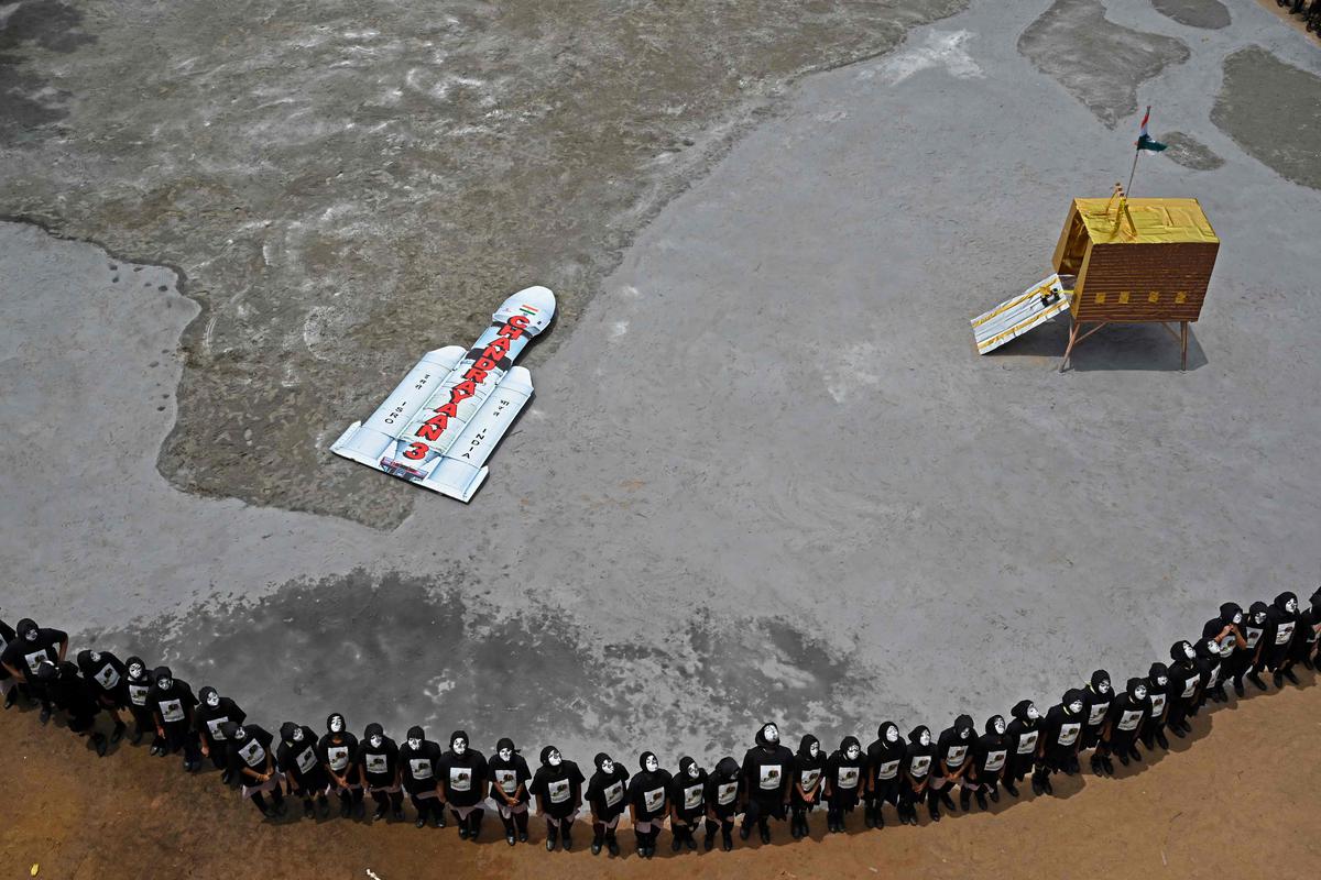 Students with painted faces form a chain around a replica of the Chandrayaan-3 spacecraft, in Chennai on August 22, 2023. 