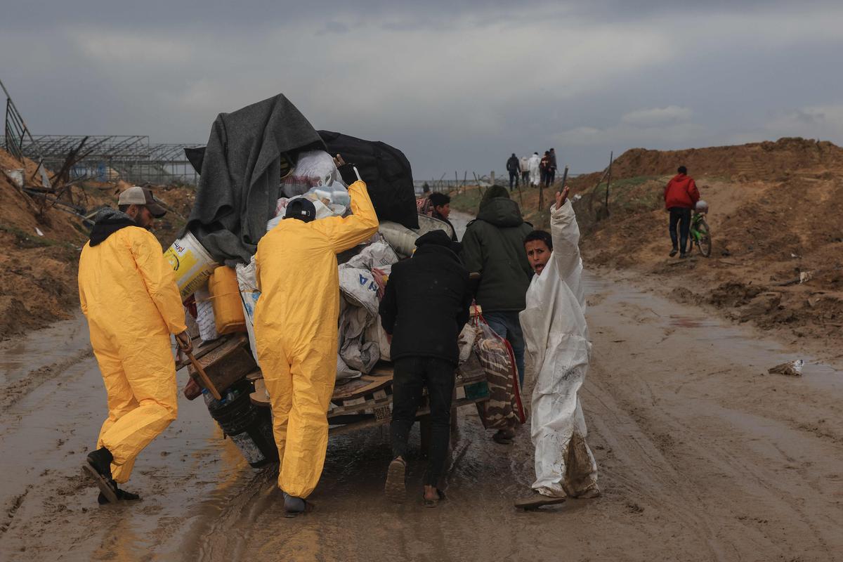 Palestinians, some wearing Hazmat suits left over from the Coronavirus pandemic to keep warm, transport some of their belongings as the flee Khan Yunis in the southern Gaza Strip further south on February 2, 2024, amid ongoing battles between Israel and the militant group Hamas. 