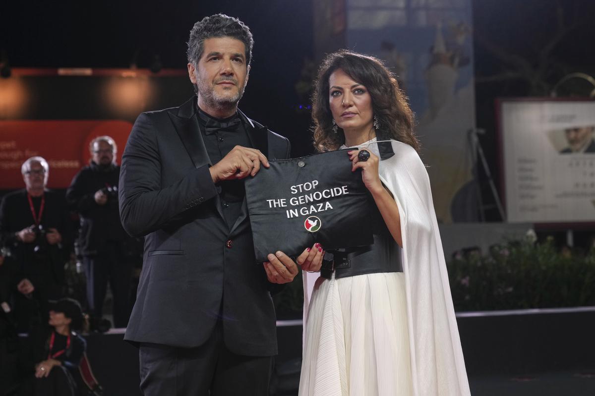 Nabil Ayouch, left, and director Maryam Touzani hold a bag which has written on it ‘Stop The Genocide in Gaza’ on the red carpet for the film ‘Calle Malaga’ during the 82nd edition of the Venice Film Festival in Venice, Italy, on Friday, Aug. 29, 2025. Nabil Ayouch, left, and director Maryam Touzani hold a bag which has written on it ‘Stop The Genocide in Gaza’ on the red carpet for the film ‘Calle Malaga’ during the 82nd edition of the Venice Film Festival in Venice, Italy, on Friday, Aug. 29, 2025.