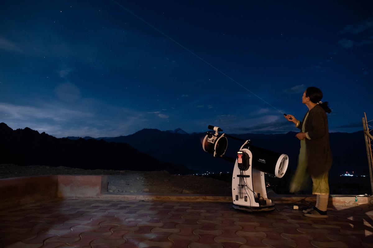 Een Ladakhi-vrouw die een telescoop bedient bij Astrostays