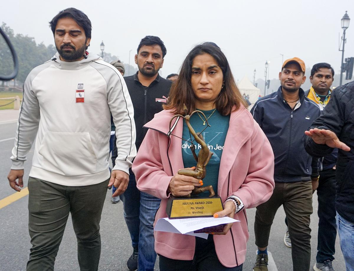 Wrestler Vinesh Phogat walks with her Arjuna and Khel Ratna Awards, India’s highest national sports awards, before leaving them on a pavement near the Prime Minister’s office as a mark of protest in New Delhi on December 30, 2023.