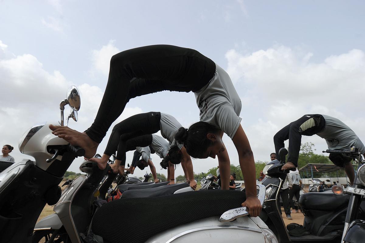 Girls perform Yoga on their two-wheeler at a ground on International Yoga Day in Ahmedabad on Tuesday, June 21, 2022. 