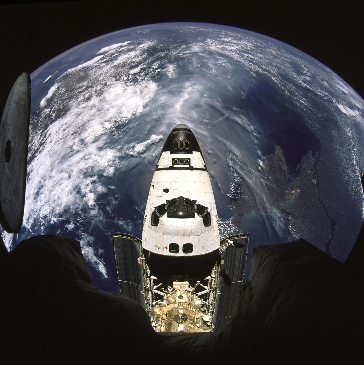 Fisheye view of Atlantis from Mir space station, backdropped against a half globe of Earth. Fisheye view of Atlantis from Mir space station, backdropped against a half globe of Earth.