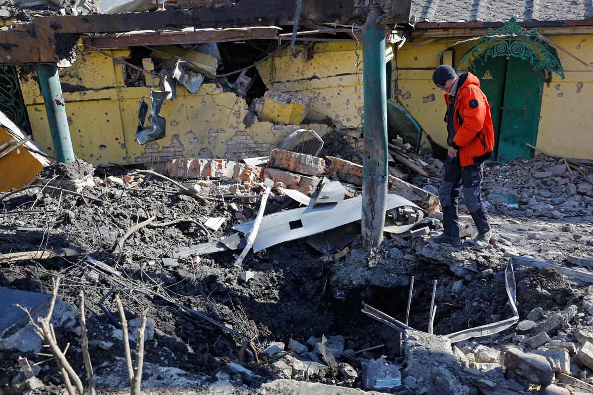 A man looks at a crater formed by recent shelling in the course of Russia-Ukraine conflict near a restaurant building in Donetsk, Russian-controlled Ukraine, February 25, 2024. 