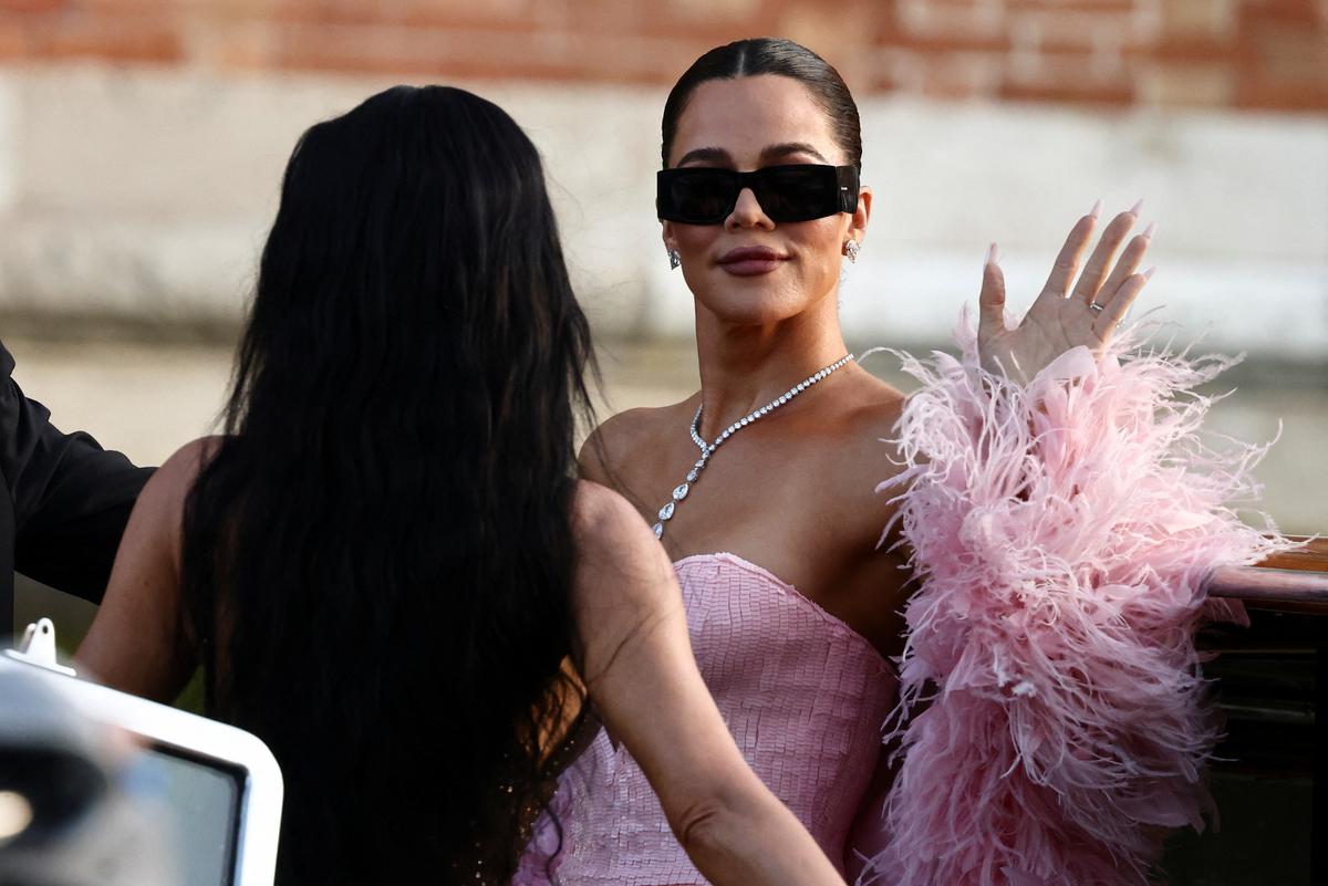 Khloe Kardashian waves on a boat next to Kim Kardashian
